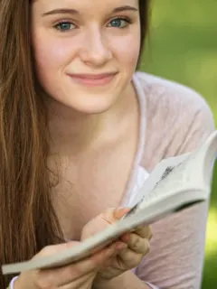 Featured image for teen romance books shows teen holding an open book.