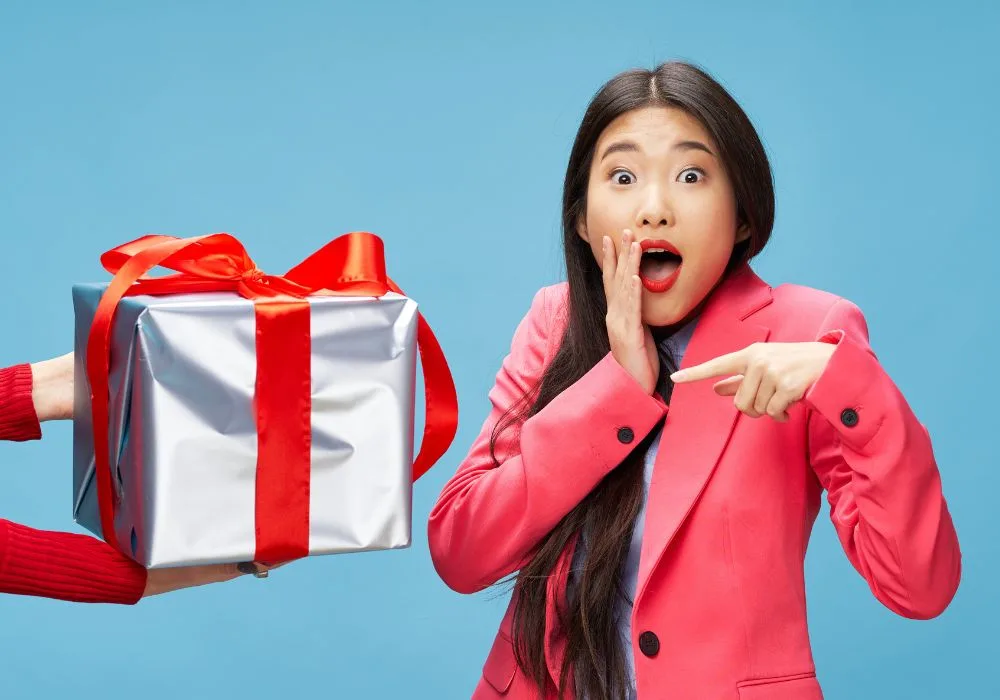 college girl in a red suit pointing at a gift box with ribbon