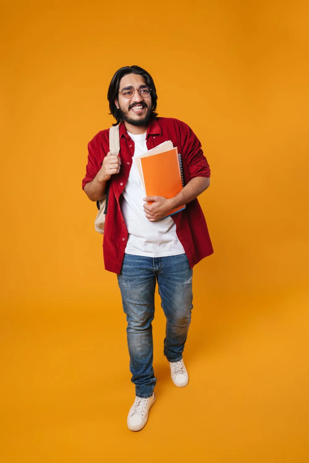 college boy all smiles as he held an orange notebook and carrying a backpack