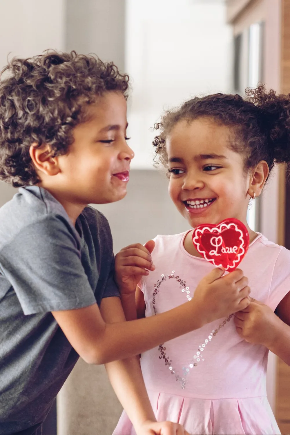 a little boy and girl holding a heart lollipop