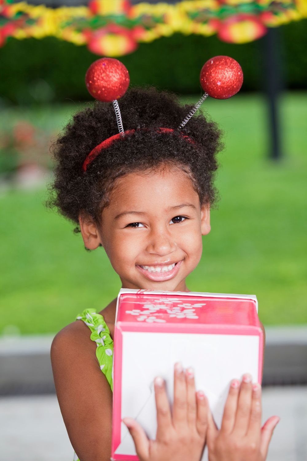 little girl holding a gift with a fun headband on